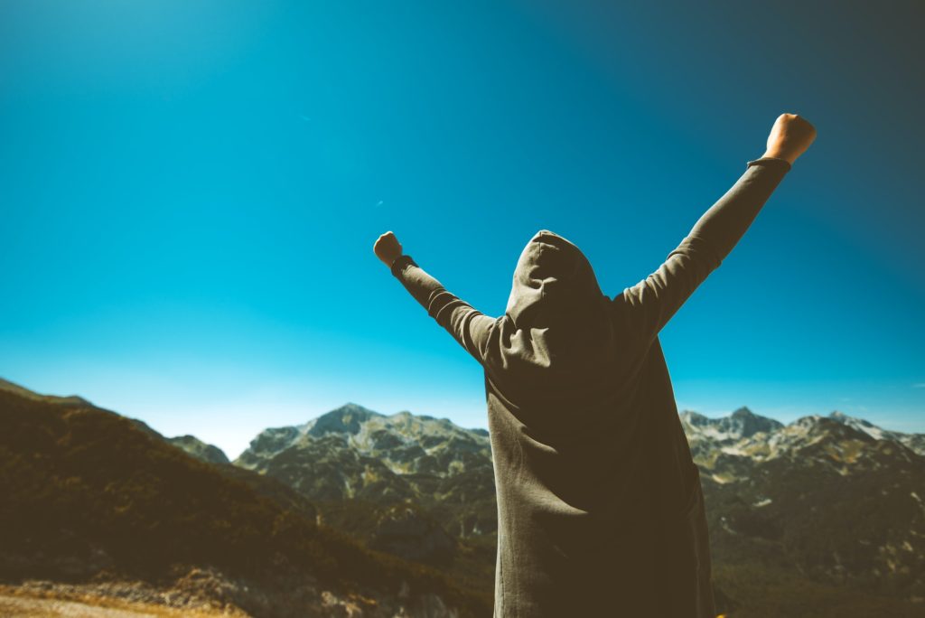Victorious female person on mountain top.